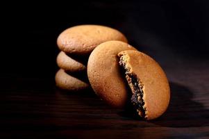 biscotti ripieni di crema al cioccolato. biscotti alla crema di cioccolato. biscotti al cioccolato marrone con ripieno di crema su sfondo nero. foto