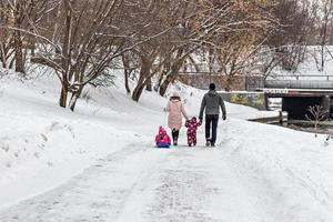 una famiglia con due bambini in slitta durante una passeggiata nel parco foto