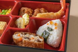 riso sushi inari avvolto in tofu essiccato con gamberi fritti e pollo fritto in set bento - stile cibo giapponese foto