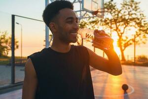 nero uomo fare gli sport nel mattina, potabile acqua su pallacanestro Tribunale su Alba foto