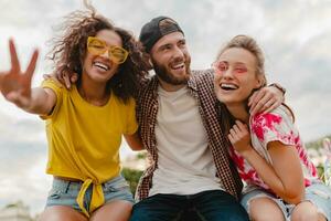 contento giovane azienda di sorridente amici seduta nel parco foto