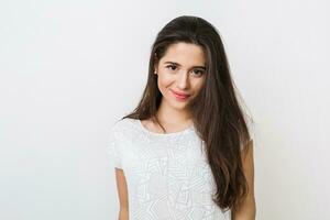 ritratto di giovane sorridente naturale guardare donna nel bianca camicetta, lungo Marrone capelli, guardare in telecamera, isolato su studio sfondo foto