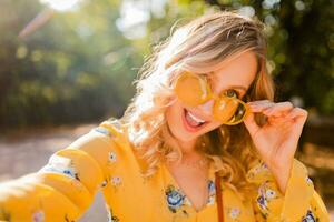 attraente biondo elegante sorridente donna nel giallo camicetta foto