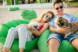 giovane attraente sorridente coppia avendo divertimento su spiaggia giocando con cani foto