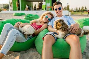 giovane attraente sorridente coppia avendo divertimento su spiaggia giocando con cani foto