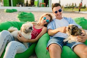 giovane attraente sorridente coppia avendo divertimento su spiaggia giocando con cani foto