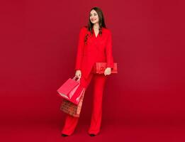 attraente donna nel rosso con shopping borse vendita su rosso sfondo foto