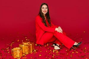 attraente donna festeggiare Natale su rosso sfondo nel coriandoli foto