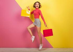 sorridente attraente donna nel elegante colorato attrezzatura salto con shopping borse foto