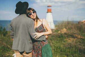 giovane fricchettone coppia indie stile nel amore a piedi nel campagna, faro su sfondo foto