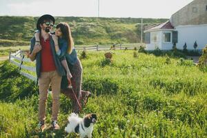 giovane elegante fricchettone coppia nel amore a piedi con cane nel campagna foto