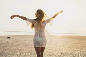 sottile bellissimo donna nel bianca cotone vestito a piedi su tropicale spiaggia foto