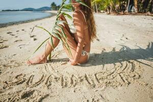 giovane magro donna nel bianca bikini costumi da bagno Tenere foglia di palma albero foto