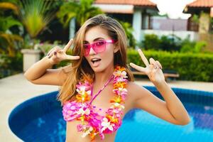 sexy donna su estate vacanza avendo divertimento a piscina indossare bikini e rosa occhiali da sole foto