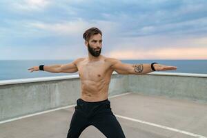 attraente bello uomo con atletico forte corpo fare mattina yoga asana all'aperto foto