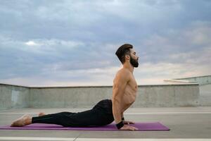 attraente bello uomo con atletico forte corpo fare mattina yoga asana all'aperto foto