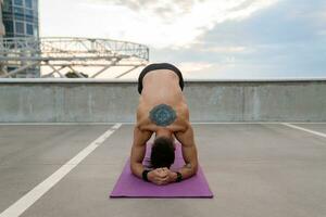 attraente bello uomo con atletico forte corpo fare mattina yoga asana all'aperto foto