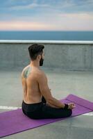 attraente bello uomo con atletico forte corpo fare mattina yoga dzen meditazione foto