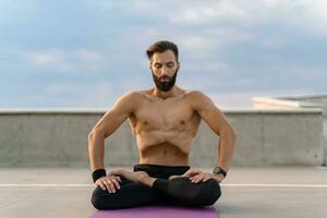 attraente bello uomo con atletico forte corpo fare mattina yoga asana all'aperto foto