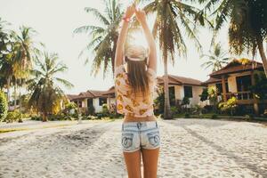 attraente fricchettone donna seduta su spiaggia ascoltando per musica su cuffie foto