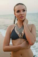 giovane bellissimo biondo donna prendere il sole su sabbia spiaggia nel bikini nuoto completo da uomo, Vintage ▾ collana foto