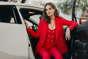 bellissimo sexy ricco attività commerciale donna nel rosso completo da uomo in posa nel bianca auto foto