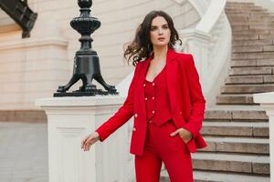 bellissimo sexy ricco attività commerciale donna nel rosso completo da uomo a piedi nel città strada, primavera estate moda tendenza foto