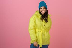 attraente attivo donna in posa su rosa sfondo nel colorato inverno giù giacca di luminosa giallo colore, sorridente divertimento, caldo cappotto moda tendenza, pazzo scioccato sorpreso viso espressione foto