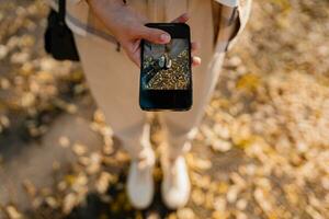 donna a piedi nel autunno utilizzando Telefono foto