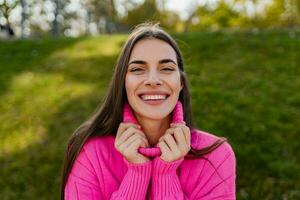 giovane sorridente donna nel rosa maglione a piedi nel verde parco foto