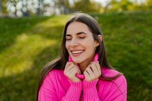 giovane sorridente donna nel rosa maglione a piedi nel verde parco foto