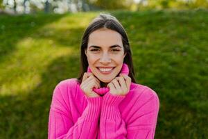 giovane sorridente donna nel rosa maglione a piedi nel verde parco foto