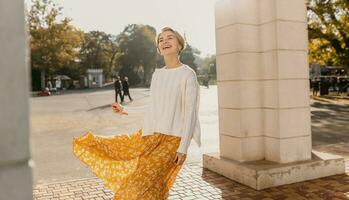 giovane bella contento sorridente donna nel giallo stampato vestito e a maglia bianca maglione foto