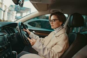 attraente elegante donna seduta nel auto vestito nel cappotto foto