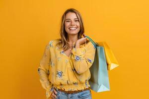 bellissimo attraente sorridente donna nel giallo camicia e jeans Tenere shopping borse foto