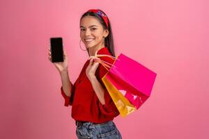 ispanico bellissimo donna nel rosso camicia sorridente Tenere Tenere shopping borse e smartphone foto