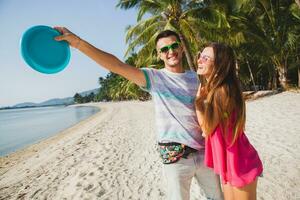 giovane coppia uomo e donna giocando volante disco su tropicale spiaggia, estate vacanza foto