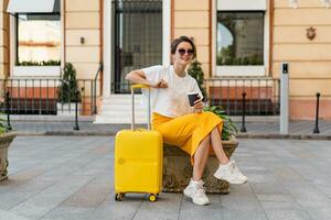 elegante donna in viaggio con giallo valigia nel Europa foto
