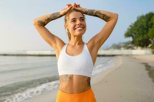 bella giovane sorridente donna fare gli sport nel il mattina nel elegante sport attrezzatura abbigliamento sportivo, magro forte corpo, salutare in forma stile di vita foto