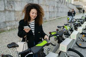 bella Riccio donna Noleggio un' bicicletta nel strada con un App foto