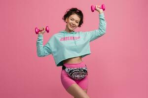 sorridente contento bellissimo donna nel elegante gli sport attrezzatura fare allenarsi su rosa sfondo isolato nel studio foto
