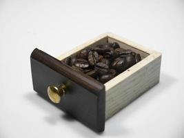 chicchi di caffè nella piccola scatola di legno dal macinino da caffè su sfondo bianco. avvicinamento foto