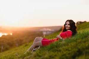 bella ragazza seduta su un pendio coperto di erba verde foto