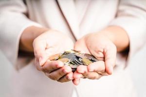 primo piano delle mani della donna di affari che tengono le monete su fondo bianco. risparmio di denaro, concetto finanziario. foto