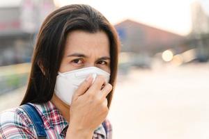 donna asiatica che indossa la maschera n95 per proteggere l'inquinamento pm2.5 e virus. covid-19 concetto di coronavirus e inquinamento atmosferico pm2.5. foto