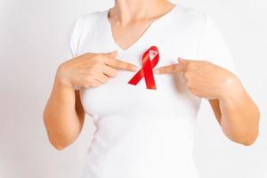 primo piano del nastro distintivo rosso sul petto della donna per sostenere la giornata contro l'AIDS. concetto di consapevolezza dell'assistenza sanitaria, della medicina e dell'AIDS. foto
