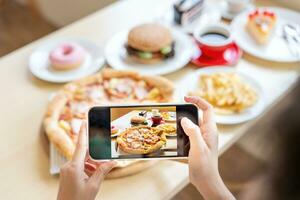 ristorante proprietario prende un' immagine di il cibo su il tavolo con un' smartphone per inviare su un' sito web. in linea cibo consegna, ordinazione servizio, influencer, revisione, sociale media, Condividere, marketing, interesse. foto