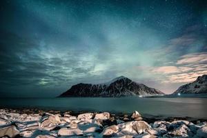 aurora boreale con stelle sulla catena montuosa con costa innevata sulla spiaggia di skagsanden foto