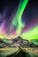 aurora boreale esplosione dell'aurora boreale sopra le montagne e la strada rurale foto