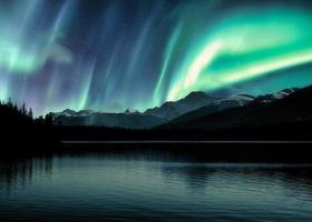 aurora boreale, aurora boreale sulle montagne rocciose canadesi nella foresta sul lago piramidale nel parco nazionale di Jasper foto